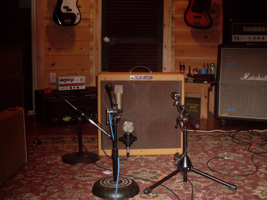 A microphone on a stand placed in front of a Fender Bassman guitar amplifier cabinet.